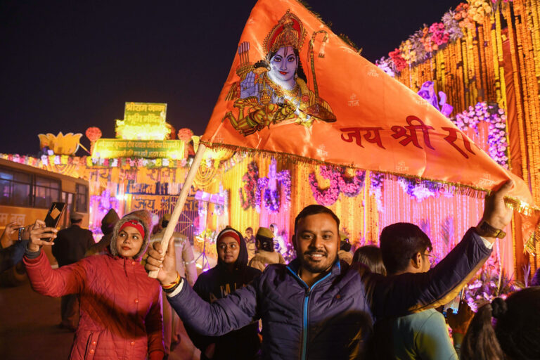 Ayodhya, Jan 21 (ANI): A devotee holds the saffron flag of Lord Ram in front of the Ram Temple entrance on the eve of its Pran Pratishtha ceremony, in Ayodhya on Sunday. (ANI Photo/Amit Sharma)